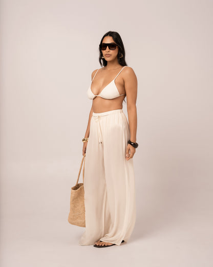 Side view of the ivory wide-leg resort pant showing its long column-like flowing leg line