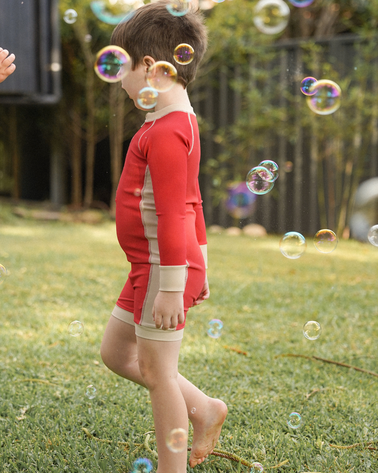 Kids melon swim surfsuit photographed outdoors with bubbles in natural light