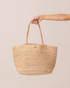 Natural raffia straw maxi tote bag held by the handle, front product view on a plain neutral background