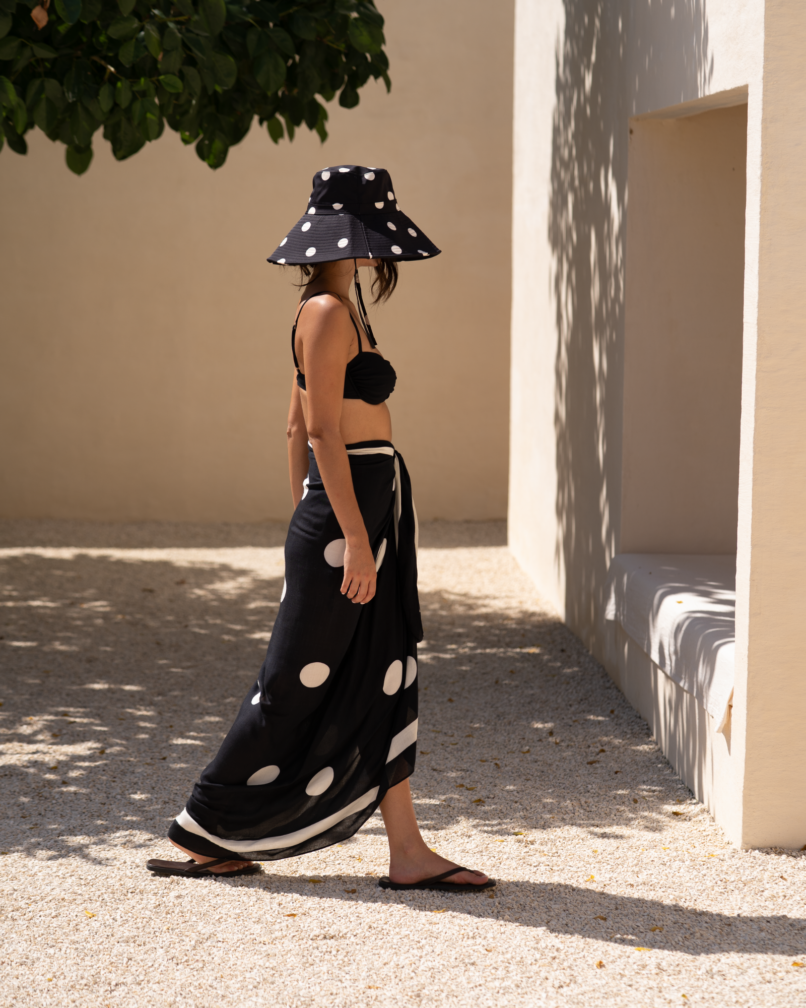 Ochre Lane Noir Dot Sarong in black polkadot print worn as a pareo wrap for resort styling