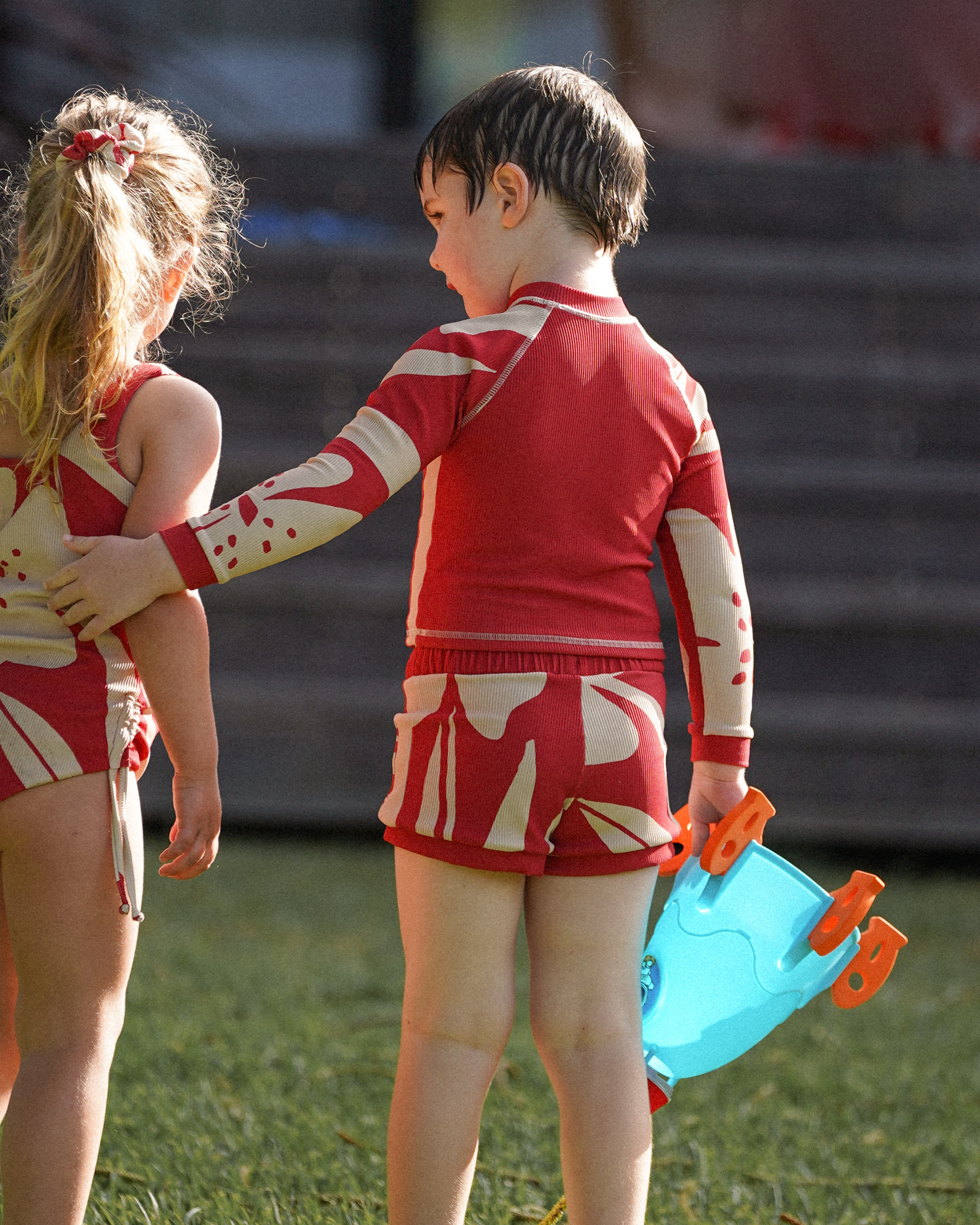 Child wearing Ochre Lane kids Solana red floral swim shorts outdoors