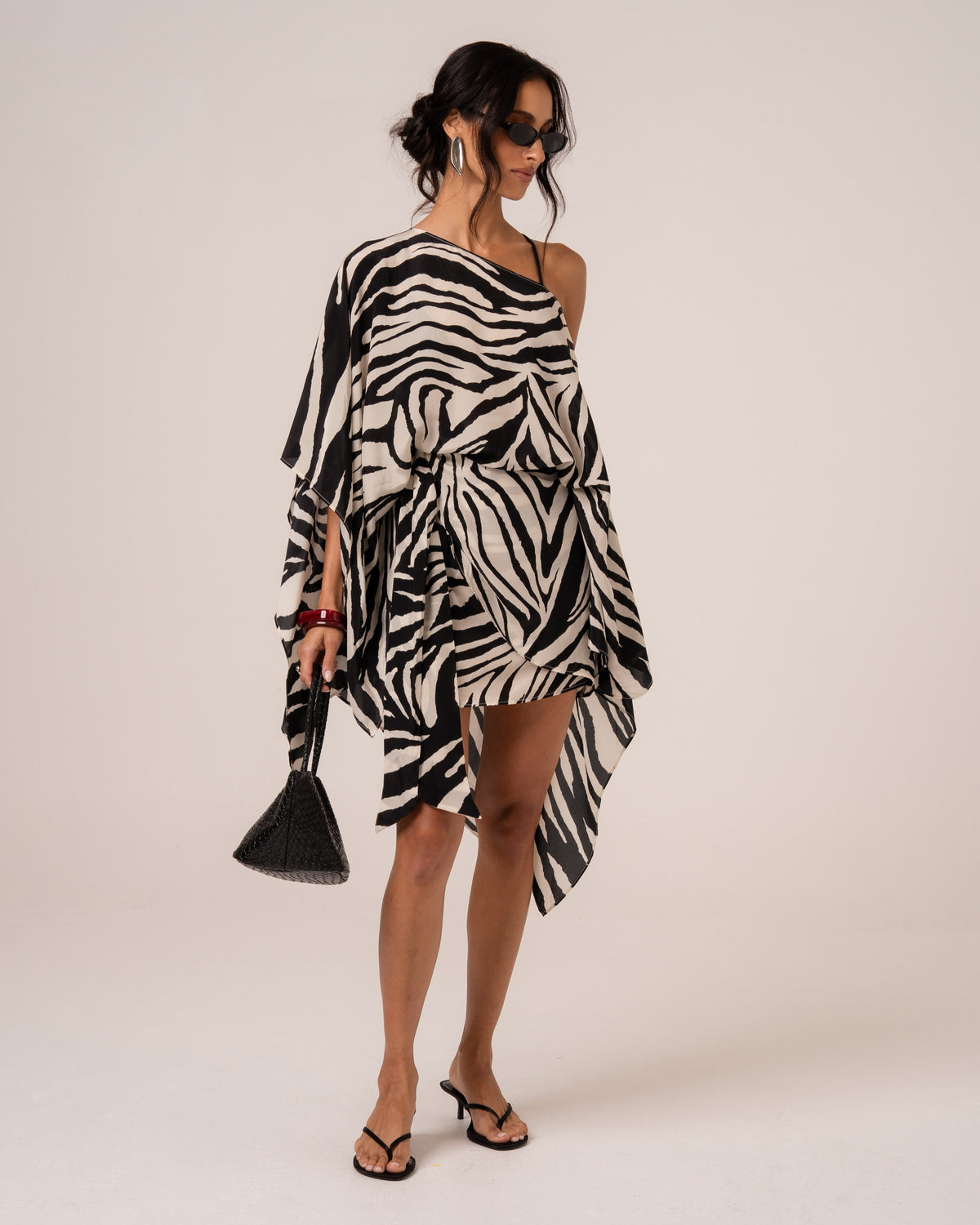 Front view of a zebra print resort cape worn off one shoulder, studio setting