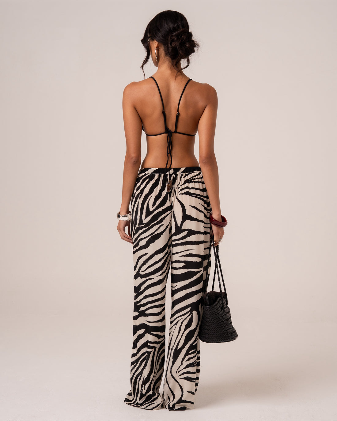 Back view of zebra print wide-leg resort pants, styled with a beaded bag