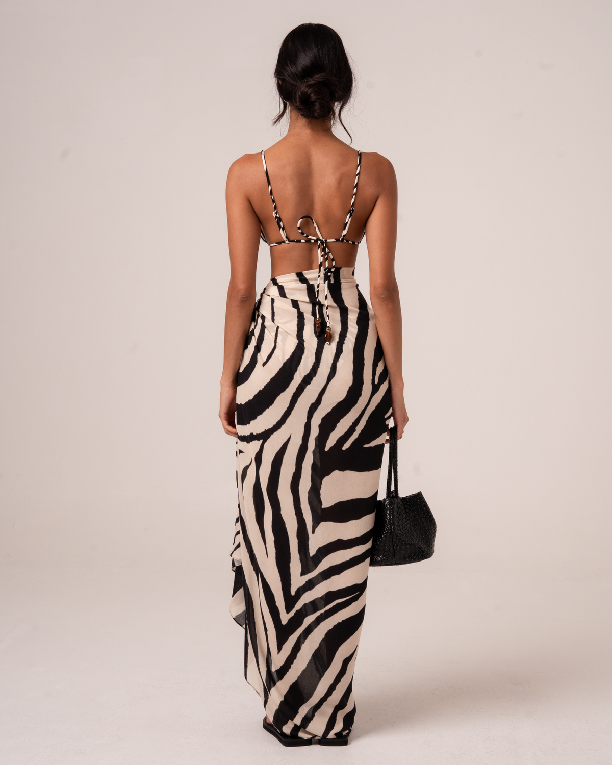 Back view of a zebra print sarong wrap skirt with a draped asymmetric hem, worn over a matching bikini top with tie-back straps