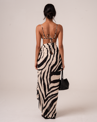 Back view of a zebra print sarong wrap skirt with a draped asymmetric hem, worn over a matching bikini top with tie-back straps