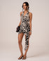 Front view of a zebra print halter wrap mini dress styled with a leather tote, studio setting